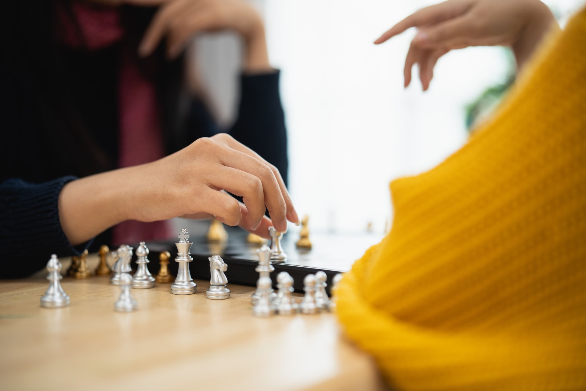 Engaging Individuals Playing Chess in Cozy Indoor Setting with Focus on Strategic Moves and Hands in Action on Chessboard