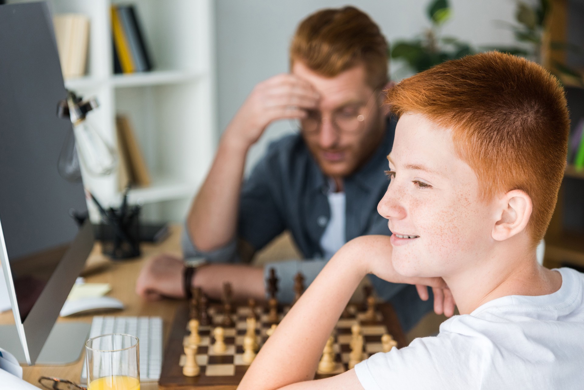 pensive father and son playing chess at home
