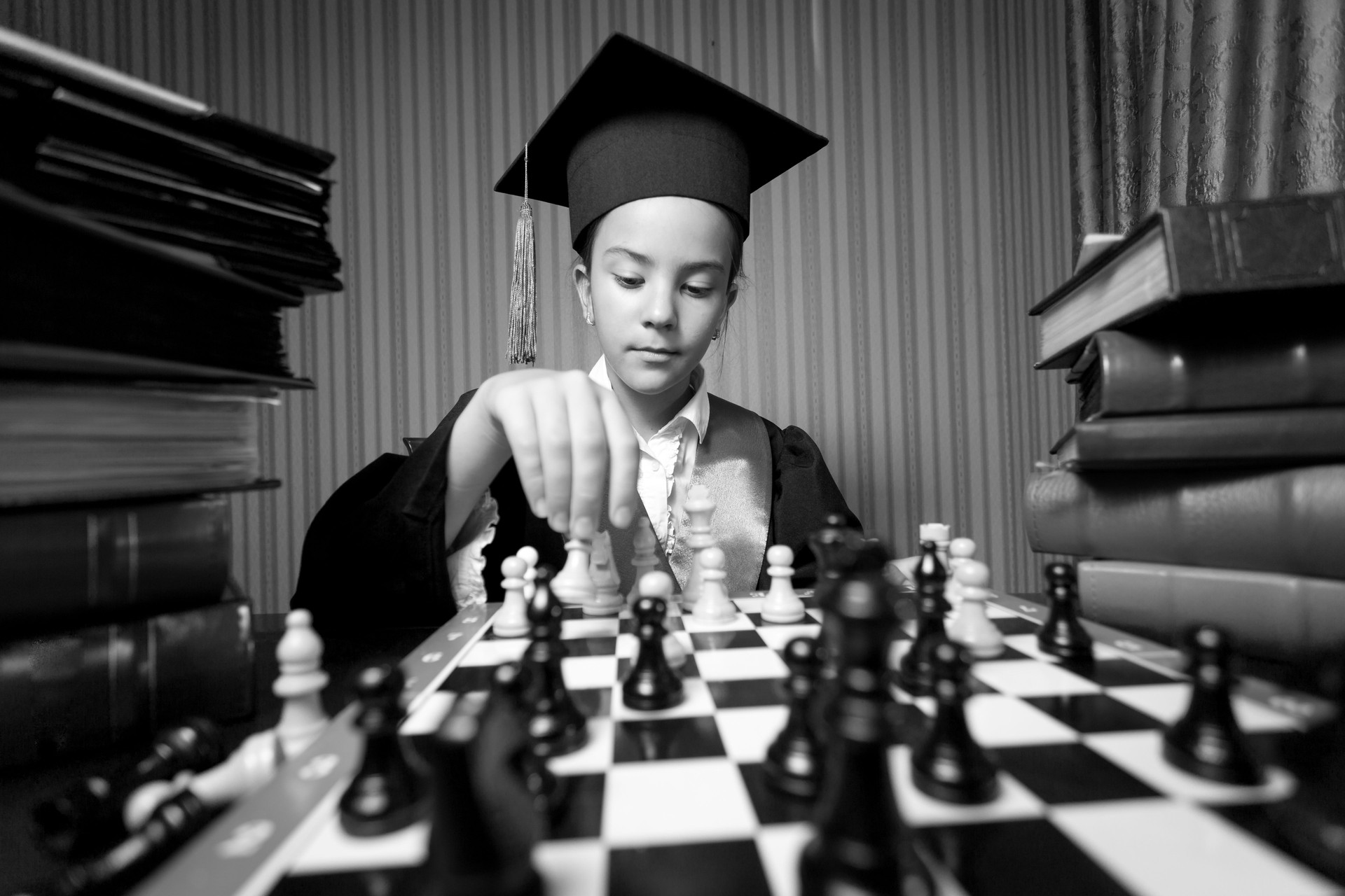 Monochrome portrait of girl graduation hat playing chess