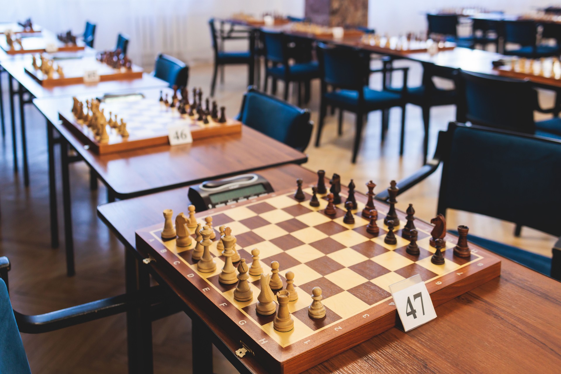 Chess tournament, kids and adults participate in chess match game outdoors in indoor hall, players of all ages play, competition in chess school club with chessboards on a table